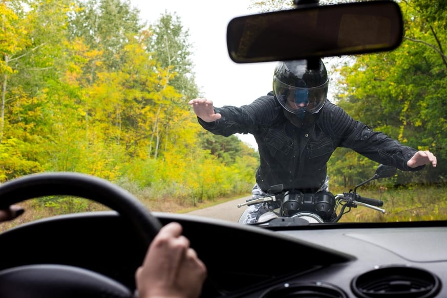 A motorcyclist seen through a car windshield dead on who is trying to slow himself before being hit in Sugar Hill, Georgia