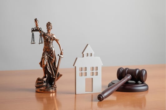 A statue of a woman holding a balance, a facade of a court house, and a gavel in Warner Robins